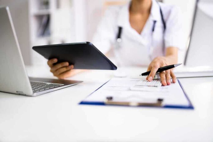 shutterstock_2081844820 Healthcare worker using tablet and filling out form