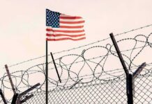 Bomb Squad Swarms U.S.-Linked Base American flag above barbed wire fence