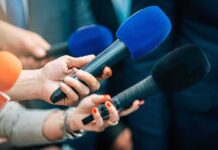 Betting Markets Shrug At AI Hype Reporters holding colorful microphones