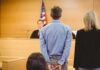 Defendant in handcuffs standing before a judge in a courtroom