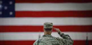 Soldier saluting before a large American flag