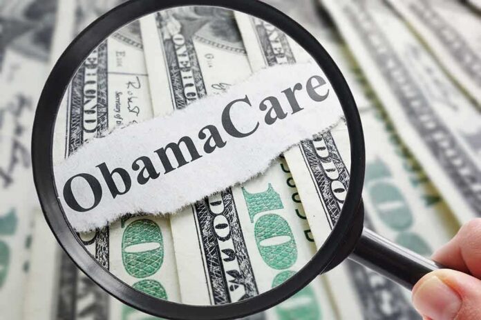 shutterstock_468939914 Magnifying glass over cash highlighting Obamacare text