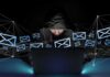 Masked Calls Terrorize Ex-White House Aide Hooded person using a laptop surrounded by email icons