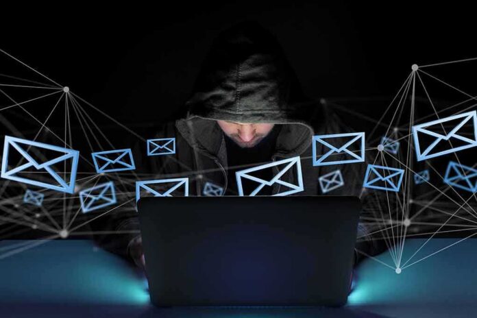 Hooded person using a laptop surrounded by email icons