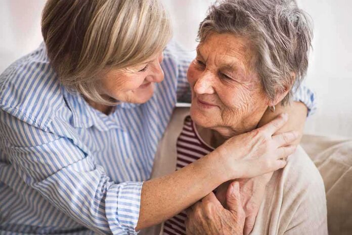 Two older women share a warm embrace on a couch