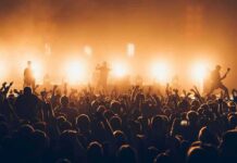Wynonna Draws A Line: Play Music Rock band performing on stage with bright backlights and cheering crowd