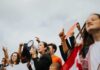 Protesters raise fists and signs as a woman speaks into a megaphone
