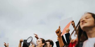 Protesters raise fists and signs as a woman speaks into a megaphone