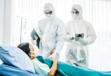 Medical staff in hazmat suits attend to a patient in a hospital bed