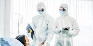 Medical staff in hazmat suits attend to a patient in a hospital bed