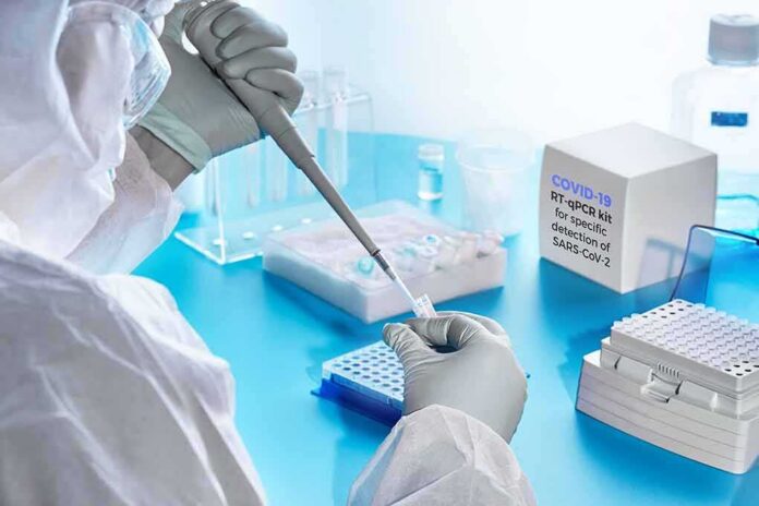 Scientist in PPE using a pipette in a COVID-19 PCR testing setup