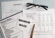 Minimum Wage Freeze Stuns Workers Minimum wage note on financial documents with glasses and pen