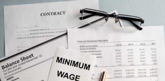 Minimum wage note on financial documents with glasses and pen
