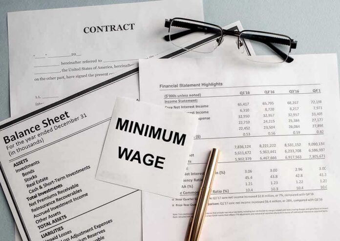 Minimum wage note on financial documents with glasses and pen