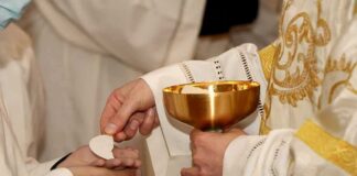 Priest gives communion wafer to a congregant