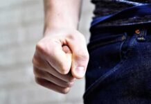 Clenched fist by a person wearing jeans