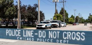 Police line barrier blocking a street with patrol vehicles behind