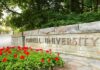 Cornell University stone entrance sign with red flowers
