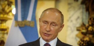Vladimir Putin speaking at a podium with microphones