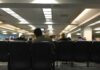 People seated in a waiting room with rows of chairs