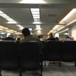People seated in a waiting room with rows of chairs