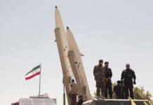 Trump Jab Triggers Iran Missile Rant Soldiers stand beside large missiles at an outdoor display