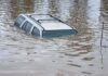 A partially submerged vehicle in floodwaters